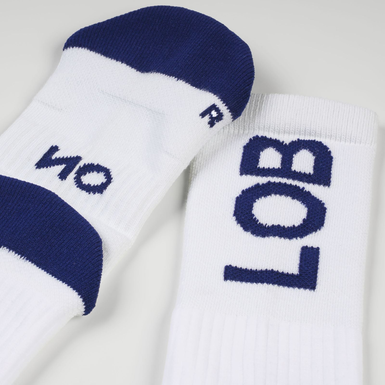 A pair of white padel socks with navy blue accents, featuring the statement 'LOB' in navy blue on the cuff and 'NO' on the side.