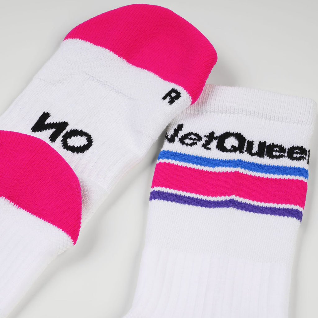A pair of white padel socks with neon pink toe and heel sections, featuring black knit branding. One sock displays 'NO' and the other shows 'Net Queen' above horizontal stripes in blue, pink, and purple.