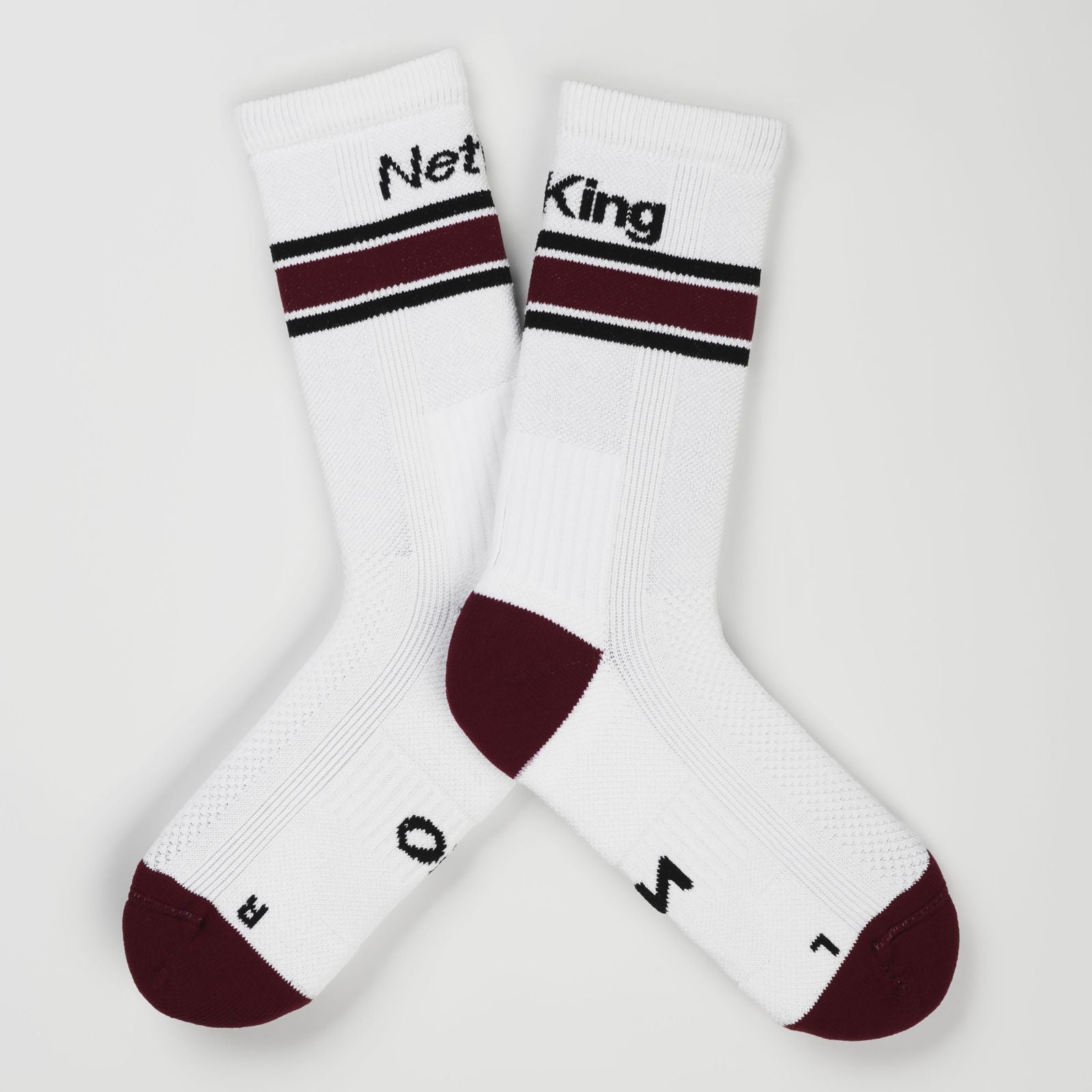 A pair of white padel socks with bordeaux accents on the heels and toes, and  bordeaux stripes near the cuff and the words 'Net King' printed in black on the cuffs.