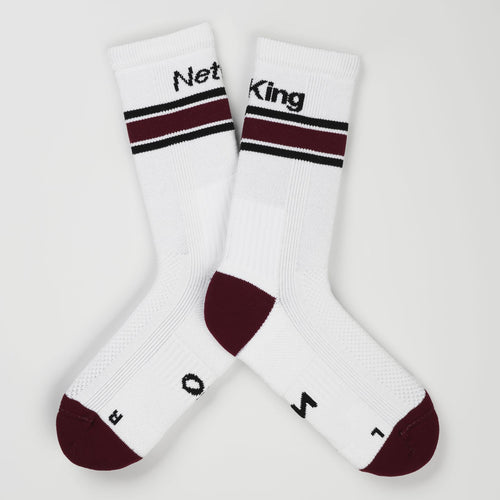 A pair of white padel socks with bordeaux accents on the heels and toes, and  bordeaux stripes near the cuff and the words 'Net King' printed in black on the cuffs.